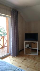 a bedroom with a tv and a large window at Brīvdienu māja INESE in Bernāti