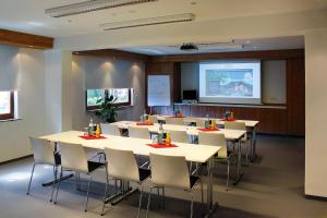 a conference room with tables and chairs and a screen at Sackmanns Wanderhotel Löwen in Baiersbronn