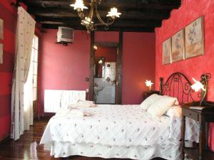 Un dormitorio con una pared roja y una cama. en Posada Trisileja, en Cos