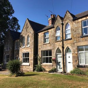 een oud bakstenen huis met witte deuren en ramen bij Climbers Cottage in Rosedale Abbey