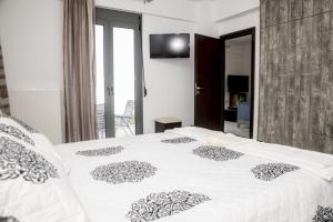 1 dormitorio con 1 cama blanca grande y TV en la pared en Villa Miron en Kamilari