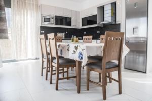 a kitchen with a table with chairs and white cabinets at Villa Miron in Kamilari