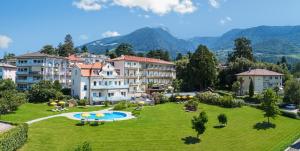 a resort with a large green lawn and buildings at Hotel Filipinum in Merano