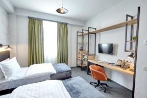 a hotel room with two beds and a desk at Graphica Tbilisi Hotel in Tbilisi City