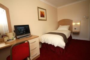 a bedroom with a bed and a desk with a television at Lloyds of Chester in Chester
