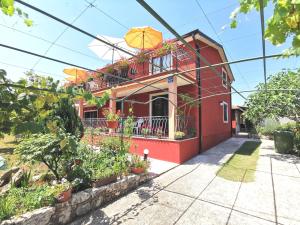 ein rotes Haus mit einem Balkon und einem Sonnenschirm in der Unterkunft Apartments Villa Amaryllis in Novigrad Istria
