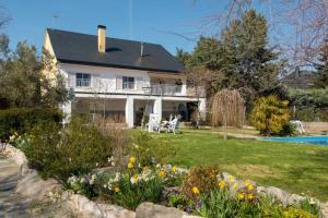 a white house with a yard with flowers at The Yellow House in Mataelpino