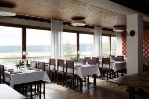 a dining room with white tables and chairs and windows at Hotel Kallgården in Järpen