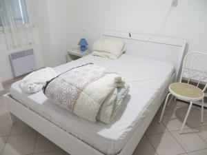 een wit bed met een kussen en een stoel in een kamer bij gite des trouilleres minimum 7nuits in Sampzon
