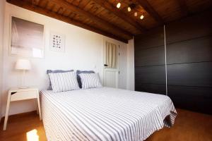a bedroom with a bed with striped sheets and a lamp at Casa Verde in Caleta De Fuste +27 photos