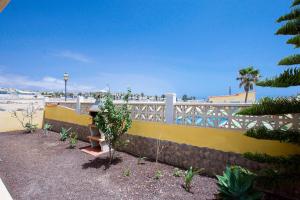 a yellow fence with a bench next to the beach at Casa Verde in Caleta De Fuste