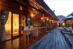 a building with a wooden deck with a bed at Royal Cottage Nusa Lembongan in Nusa Lembongan