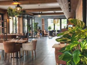 un restaurante con mesas, sillas y plantas en AZZA Hotel, en Jesenice