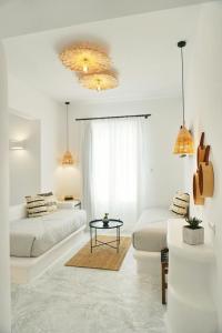 a white living room with two beds and a table at Galini Hotel in Naxos Chora
