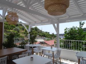 eine weiße Pergola mit Tischen und Stühlen auf einer Terrasse in der Unterkunft Galini Hellenic Hospitality in Patitiri