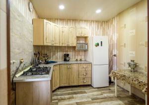 eine Küche mit Holzschränken und einem weißen Kühlschrank in der Unterkunft Tsera House in Gori