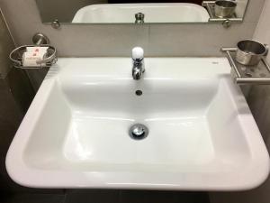 a white sink in a bathroom with a mirror at The KAHN Dormitory in Chikmagalūr +8 photos