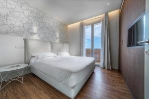 una camera da letto con un grande letto bianco e una finestra di Hotel Select Suites & Spa - Apartments a Riccione