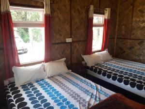 two beds in a room with red curtains at Vamoose Hornbill in Mangpu