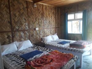 two beds in a wooden room with a window at Vamoose Hornbill in Mangpu