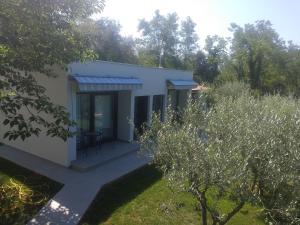 ein kleines weißes Haus mit einer Terrasse und Bäumen in der Unterkunft App Neno in Murine