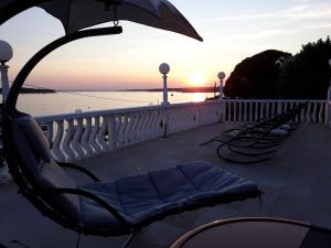 una fila de sillas sentadas en un balcón con el océano en Apartments and Rooms Vinko, en Barbat na Rabu
