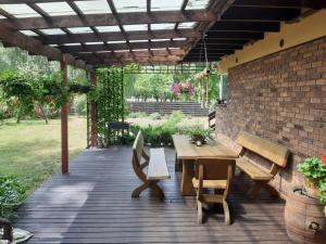 a wooden deck with a table and benches and a brick wall at Apartamentai pas Danutę in Prienai