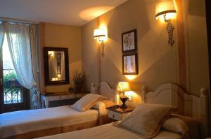 a bedroom with two beds and a mirror and lights at Hotel Casa Frauca in Sarvisé