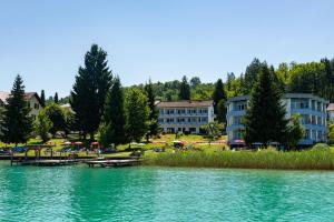 a group of buildings on the shore of a lake at Strandhotel Schabus in Velden am Wörthersee