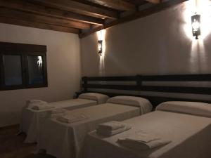 una habitación con 4 camas y mesas con toallas. en VTAR Don Benito, su casa rural en Gilena, en Gilena