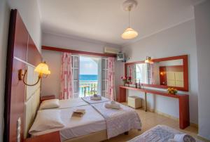 a bedroom with a bed and a view of the ocean at Agoulos Beach Hotel in Argasi