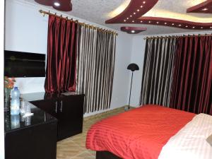 1 dormitorio con 1 cama con sábanas y cortinas rojas en Valentine Inn Luxury en Wadi Musa