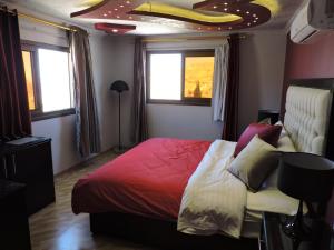 a bedroom with a bed with a red comforter and windows at Valentine Inn Luxury in Wadi Musa