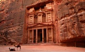 Un cammello si trova di fronte a un edificio in un canyon di Valentine Inn Luxury a Wadi Musa