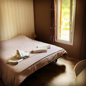 a bed with two towels on it in a room with a window at Chalet 3 chambres en Bois dans les landes n37 in Tosse