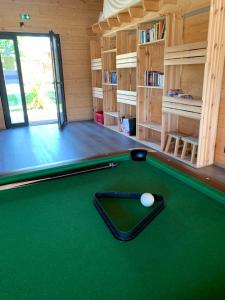 a pool table in a room with a book shelf at Chalet 3 chambres en Bois dans les landes n37 in Tosse