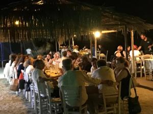 un gran grupo de personas sentadas en mesas en un restaurante en Kymata, en Palaiopoli