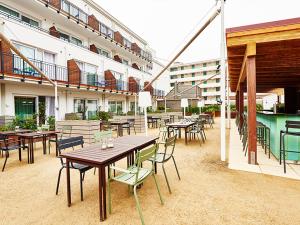 eine Außenterrasse mit Tischen und Stühlen sowie einem Pool in der Unterkunft New Wave in Norderney