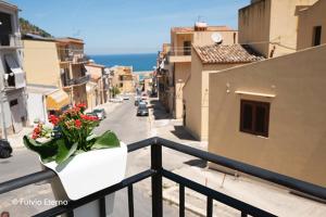 uma varanda com um vaso de flores sobre um corrimão em Casa vacanza oscar em Castellammare del Golfo