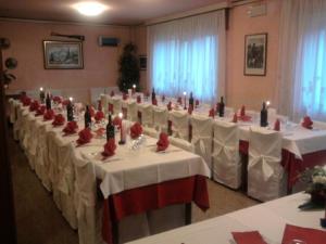 FozaにあるHotel Monte Fiorの白いテーブル、赤い椅子、キャンドルが備わる宴会場