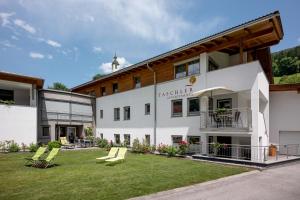ein großes weißes Gebäude mit einem Rasen davor in der Unterkunft Ferienwohnung Taschler in Ramsau im Zillertal