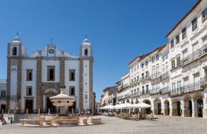 a building with a fountain in the middle of a street at Casa das Arcadas, free Garage - Praça de Giraldo in Évora