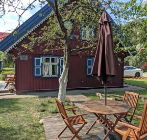a table and chairs and an umbrella in front of a house at Poilsio burės in Nida