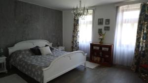 1 dormitorio con cama blanca y lámpara de araña en Öregporta Vendégház en Bazsi