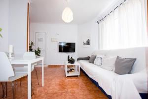 a white living room with a white couch and a table at Casa Verde in Caleta De Fuste