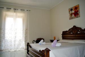 una camera con due letti con lenzuola bianche e una finestra di Rua House a Corleone