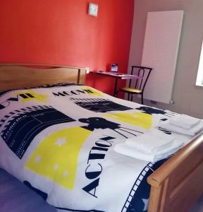 a bed with a comforter on it with a table at Le Terminus fasthotel soissons centre in Soissons