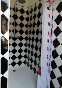 a shower with a black and white checkered wall at Le Terminus fasthotel soissons centre in Soissons