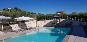 a swimming pool with chairs and umbrellas next to a building at Agriturismo La Madonnina in Montefalco