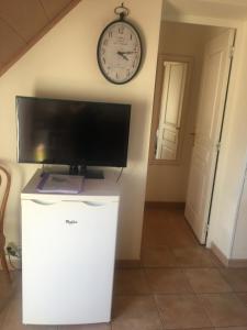 a television on top of a refrigerator in a room with a clock at Villanna in Sainte Anne d'Auray